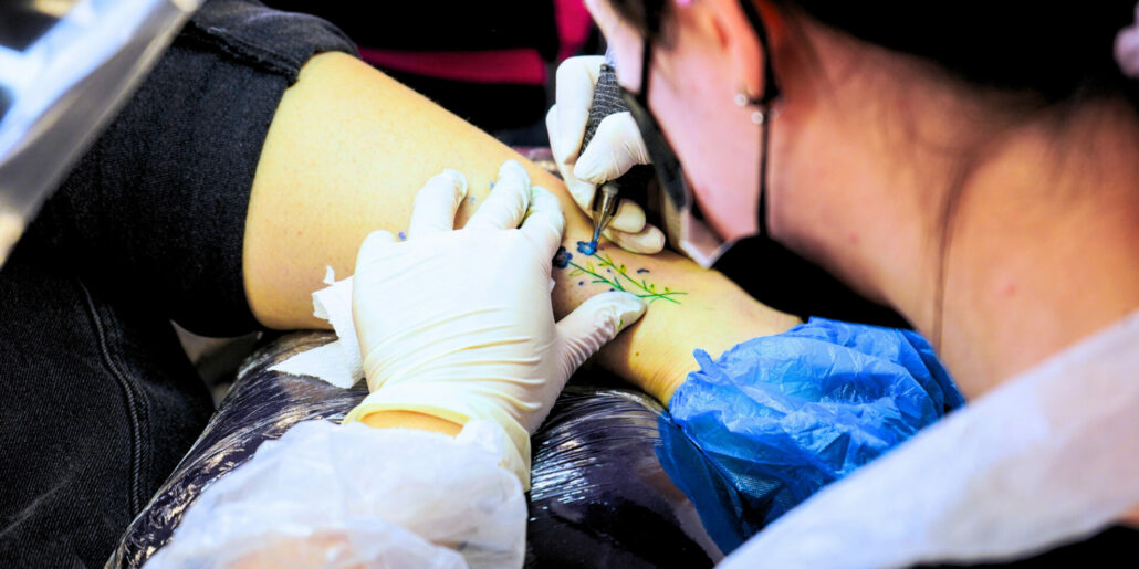 Professionista che realizza un tatuaggio pittorico su cliente